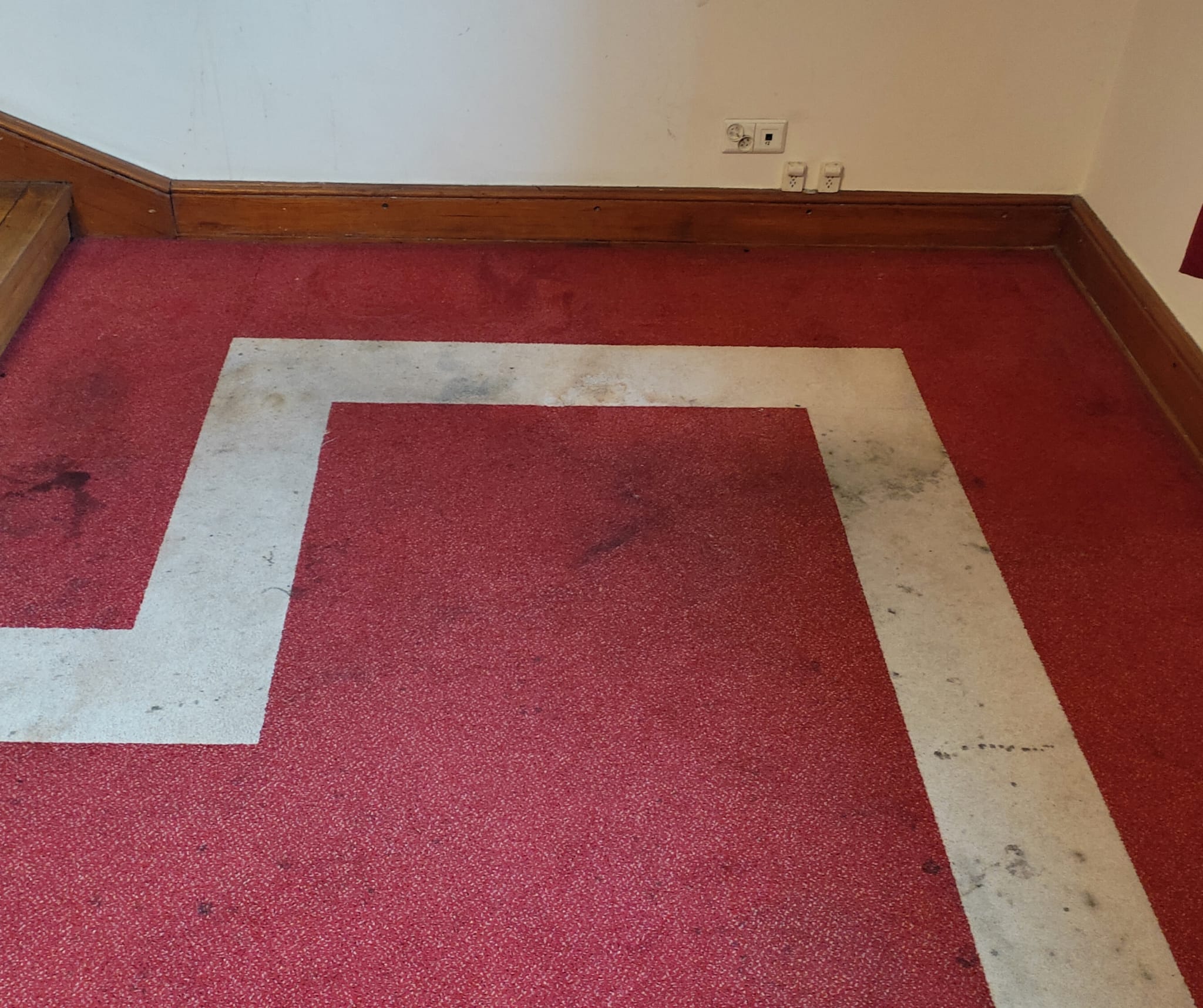Czerwona wykładzina przed praniem, zabrudzone ciągi komunikacyjne